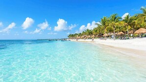 A beach with clear turquoise water, white sand, and palm trees. - Amazing Akumal Townhouse With Private Plunge Pool (Akumal)