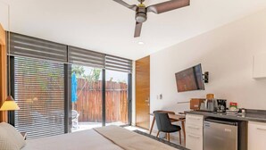 A bedroom with a bed, a desk, a chair, a television, and a kitchenette. - Amazing Akumal Townhouse With Private Plunge Pool (Akumal)