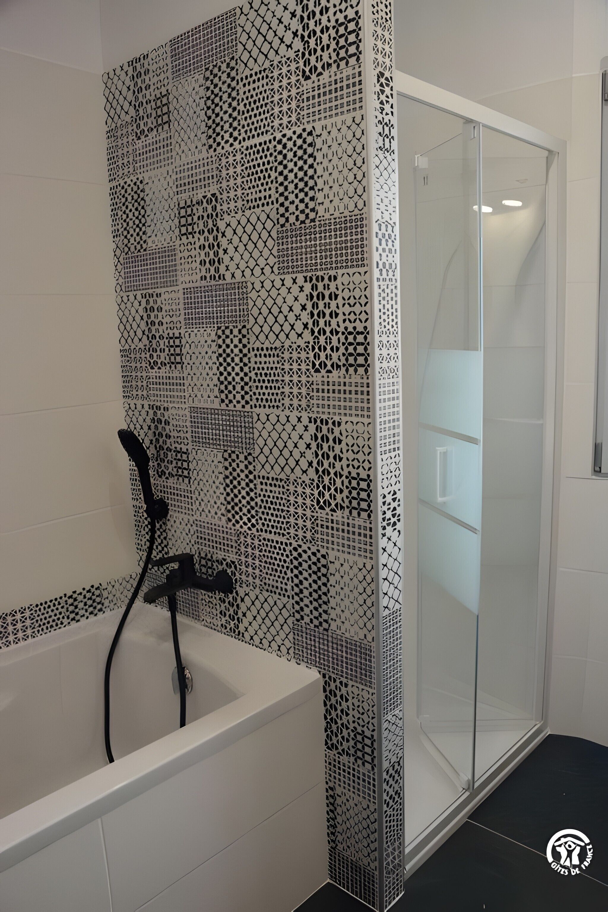 Ein modernes Badezimmer mit einer weißen Badewanne, einer Dusche mit Glastür und einer dekorativen Wand mit Fliesen.