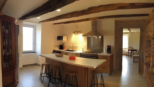 A kitchen with a central island, bar stools, a stove, and a microwave.