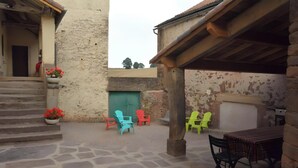 A courtyard with stone steps, a green door, and colorful plastic chairs.