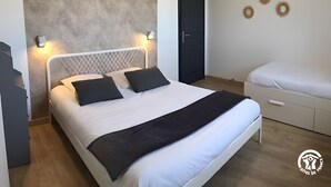 A bedroom with a bed, bedside tables, a wardrobe, and a door.