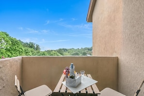 Un balcón con una mesa para dos, con vistas a un paisaje verde exuberante.