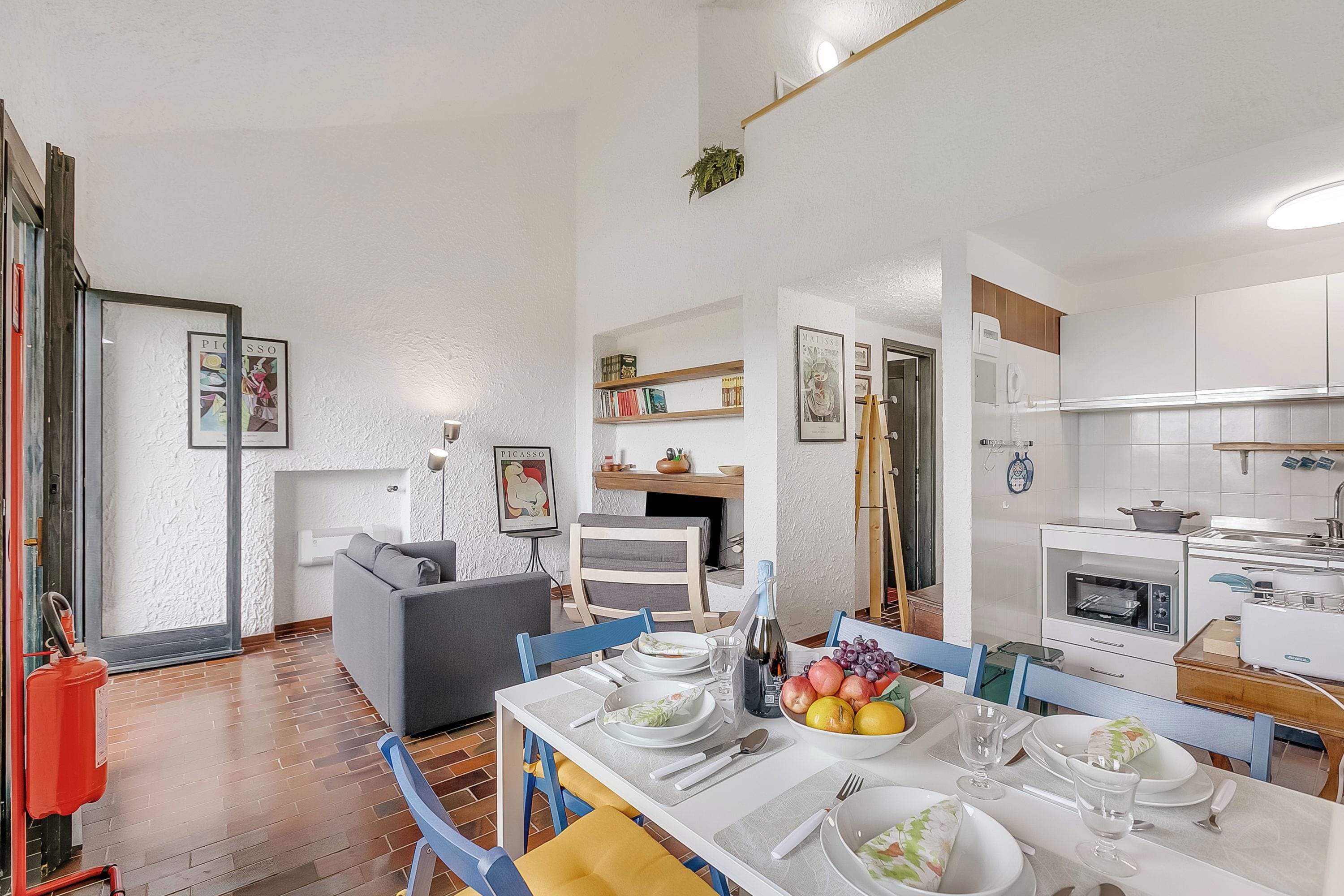 Une cuisine moderne avec des armoires blanches, un four encastré et un coin repas avec une table dressée pour quatre personnes.