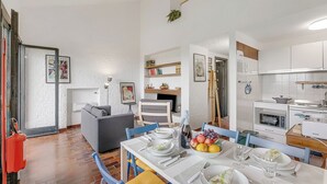 Eine moderne Küche mit weißen Schränken, einem eingebauten Backofen und einem Essbereich mit Tisch für vier Personen.