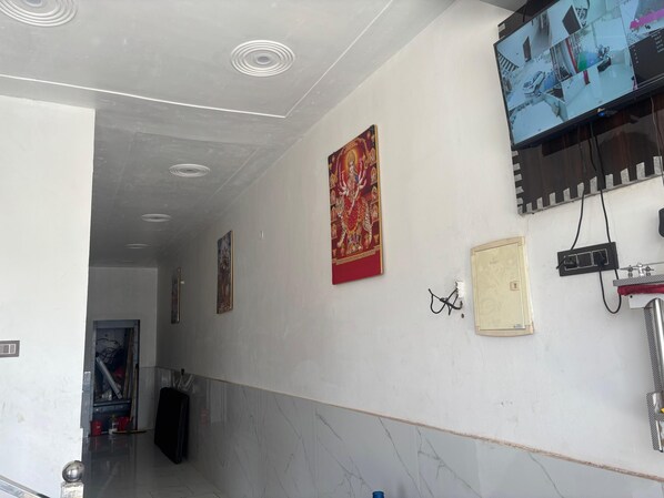 A hallway with a ceiling featuring circular light fixtures, a wall-mounted security camera, and a framed artwork.