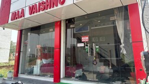 A hotel with a red and white facade, large glass windows, and a 'Room Available' sign. - Maa Vaishno Dham (Vrindavan)