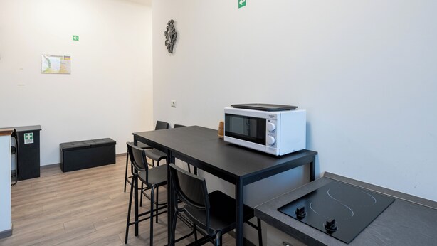 A modern room with a table, chairs, a microwave, a small cabinet, and a map on the wall. -  ReRent Rooms - 36 Trionfale Guesthouse (Rome)