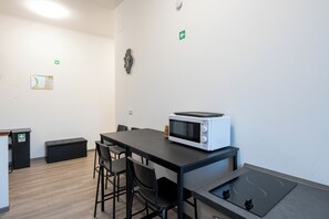 A modern room with a table, chairs, a microwave, a small cabinet, and a map on the wall. -  ReRent Rooms - 36 Trionfale Guesthouse (Rome)