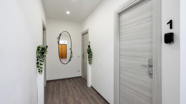 A hallway with a wooden floor, white walls, and two doors with numbers 1 and 2. -  ReRent Rooms - 36 Trionfale Guesthouse (Rome)