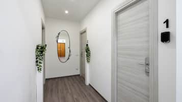Un pasillo con suelo de madera, paredes blancas y dos puertas con los números 1 y 2.