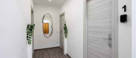 A hallway with a wooden floor, white walls, and two doors with numbers 1 and 2.