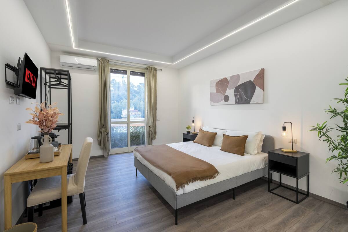 A modern bedroom with a bed, bedside tables, a desk, and a chair.