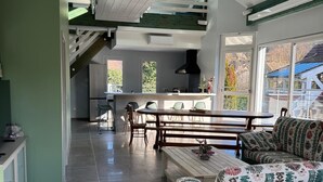 Un amplio espacio de estar con techo alto, una mesa de comedor y un sofá.