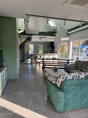 A spacious living area with a high ceiling, a dining table, and a sofa. - Loft 4/5 pers rénové - Jardin - Billard privé (Osenbach)