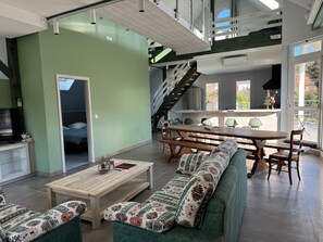 A modern interior with a dining area, sofa, staircase, and a view of the outdoors. - Loft 4/5 pers rénové - Jardin - Billard privé (Osenbach)