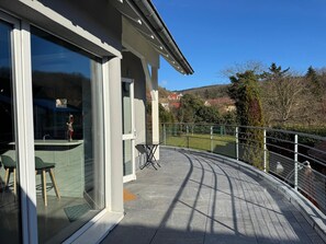A modern building with large glass windows, a balcony with a metal railing, and a view of a hilly landscape. - Loft 4/5 pers rénové - Jardin - Billard privé (Osenbach)