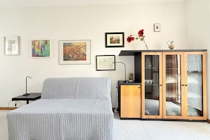 Een slaapkamer met een bed, nachtkastje, kast en wanddecoratie.