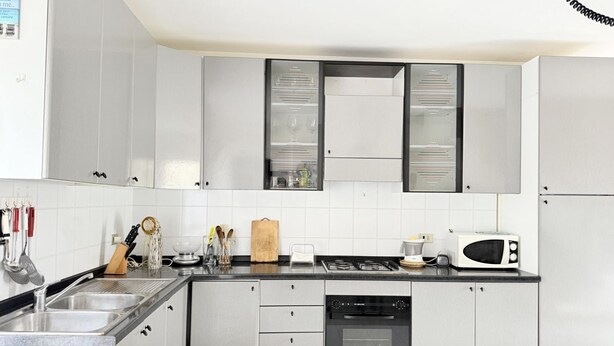 A kitchen with white cabinets, a microwave, a stove, and a dishwasher. - SE249 – Montemarciano, spacious three-room apartment near the sea (Montemarciano)