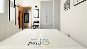 A bedroom with a bed, a wardrobe, a chair, and a door leading to another room. - SE249 – Montemarciano, spacious three-room apartment near the sea (Montemarciano)