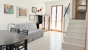 A modern living room with a sofa, dining table, and artwork on the walls. - SE249 – Montemarciano, spacious three-room apartment near the sea (Montemarciano)