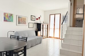 Ein modernes Wohnzimmer mit einer Couch, einem Esstisch und Kunstwerken an den Wänden.