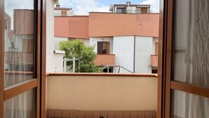 A balcony with a view of neighboring buildings, a tiled floor, and a small plant. - SE249 – Montemarciano, spacious three-room apartment near the sea (Montemarciano)