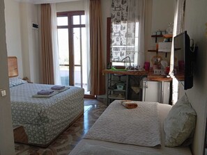 Una habitación con dos camas, un kitchenette, televisión y ventana con cortinas.