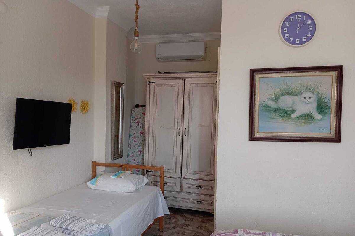 A bedroom with a bed, a wardrobe, a television, and a clock on the wall.