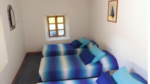 A room with a wooden ceiling, a window with a view, a bed with patterned bedding, and a patterned floor. - Tighremt Assif Melloul (Anergui)