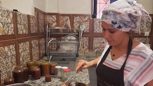 A person cooking in a kitchen with a stove, pots, and a spice rack. - Tighremt Assif Melloul (Anergui)