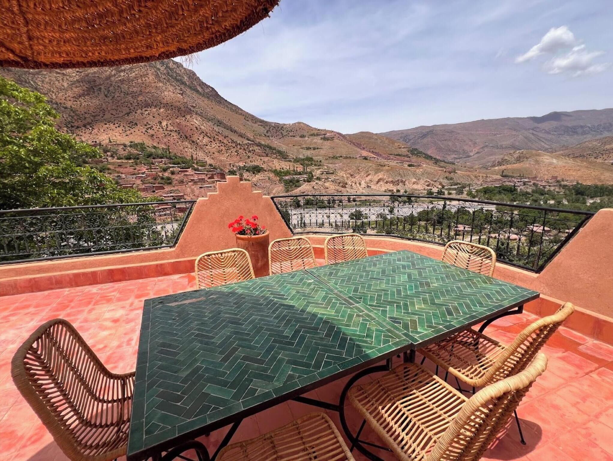 A terrace with a table and chairs, overlooking a mountainous landscape.