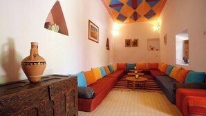 A living room with a large sectional sofa, a wooden cabinet, and a decorative ceiling. - Tighremt Assif Melloul (Anergui)