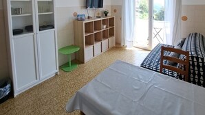 Ein Zimmer mit einem Bett, einem Fernseher, einer Küchenzeile und Blick aus dem Fenster.