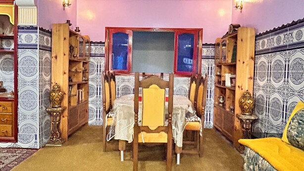 Comedor con mesa y sillas, pared con estampado y techo con molduras decorativas.
