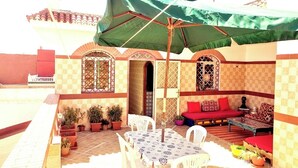 Un patio con mesa y sillas, un sofá y un amplio paraguas.