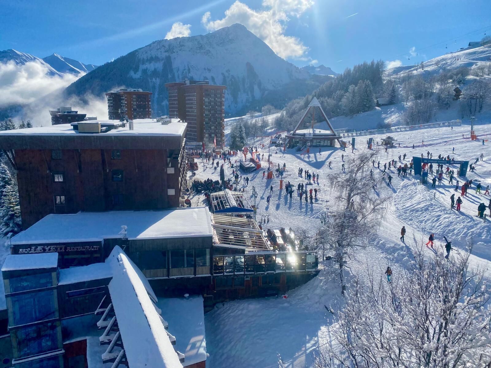Een skigebied met gebouwen, een skilift en een berg op de achtergrond.