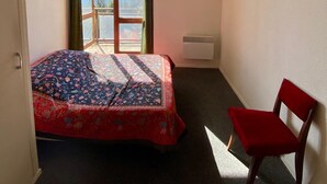 Una camera da letto con un letto, una sedia, una finestra vista e un lampadario al soffitto.