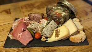 Liha-, juusto- ja suolakurkkulajitelma tarjoiltuna liitulevyllä.