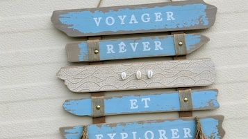 Een wandbord met de woorden 'VOYAGER', 'RÊVER', 'ET' en 'EXPLORER' in een rustieke stijl.