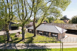 A building with a sloped roof, surrounded by trees and a fence.