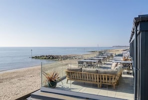 Eine Strandterrasse mit Sitzgelegenheiten und Blick aufs Meer.