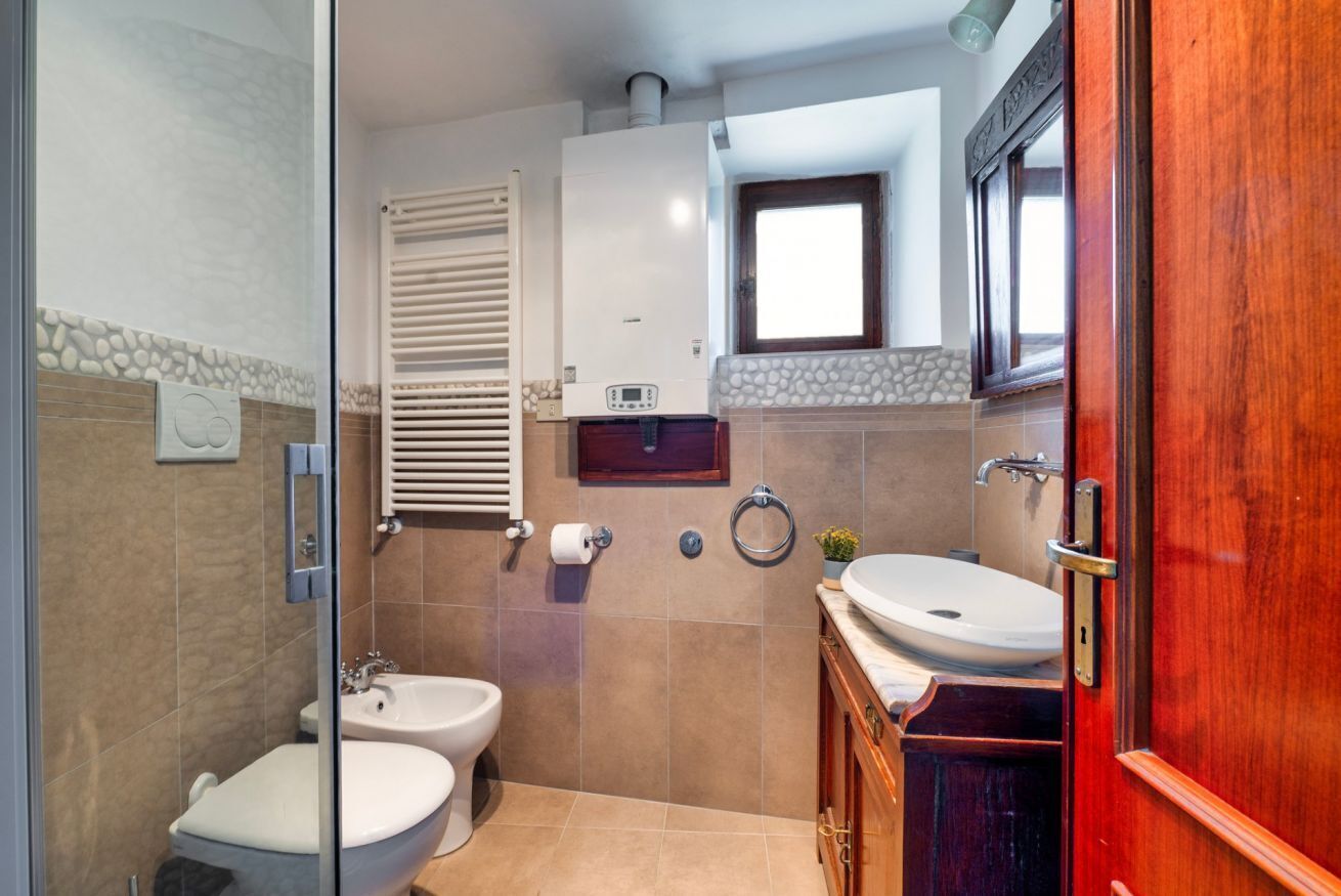 Ein Badezimmer mit Toilette, Bidet und Waschbecken, einem Handtuchhalter und einem Fenster.