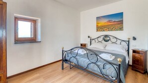 Une chambre à coucher avec un lit, une fenêtre, un tableau et une table de chevet.