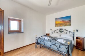 A bedroom with a bed, a window, a painting, and a nightstand. - A comfortable 90 sqm apartment, accommodating up to 5 people, spread over two levels connected by an internal staircase.The property is located in Spello, a characteristic village on the slopes of Mount Subasio, close to the historic center and in a Limi (Spello)