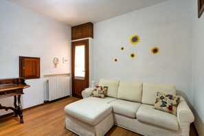 A living room with a sofa, a wooden cabinet, and a radiator. - A comfortable 90 sqm apartment, accommodating up to 5 people, spread over two levels connected by an internal staircase.The property is located in Spello, a characteristic village on the slopes of Mount Subasio, close to the historic center and in a Limi (Spello)