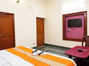 Une chambre d’hôtel équipée d’un lit, d’un téléviseur fixé au mur, d’un bureau et d’une chaise.