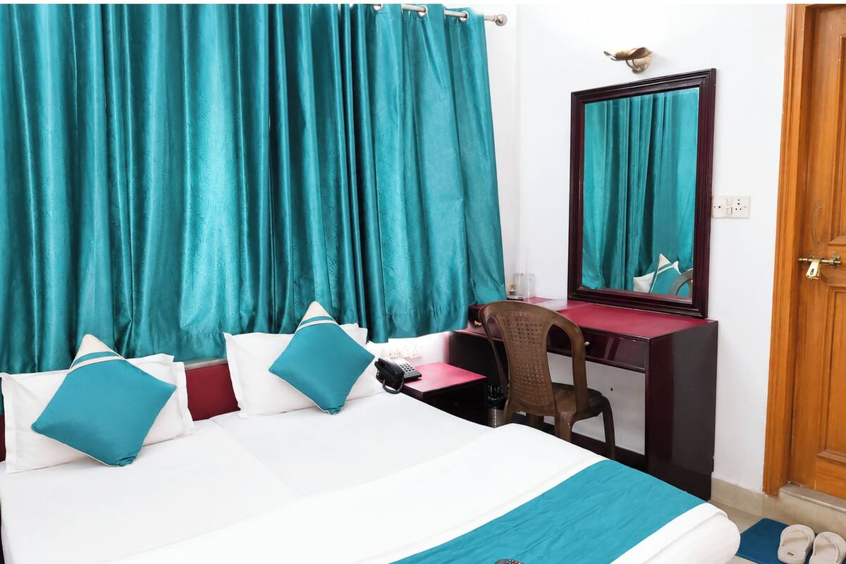 Ein Hotelzimmer mit einem Bett, einem Schreibtisch, einem Stuhl, einem Spiegel und einer Tür.