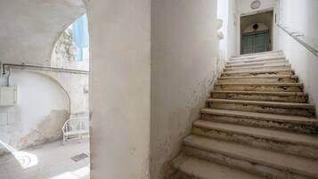 Eine Treppe führt zu einer Tür mit blauem Rahmen, einer weißen Bank und einem Metallgeländer.