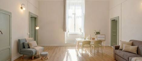 Una habitación amplia con comedor, sofá y ventana con cortinas traslúcidas.